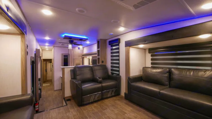 Inside an RV rental: a cozy living area with dark leather sofas, stylish wood-look flooring, and cool blue ceiling lights.. Forest River Cherokee Arctic Wolf 2022
