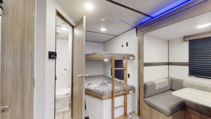 Inside this RV rental: functional bunk beds, a compact bathroom, and an L-shaped dinette area for comfortable travel.. Crossroads Zinger 2022