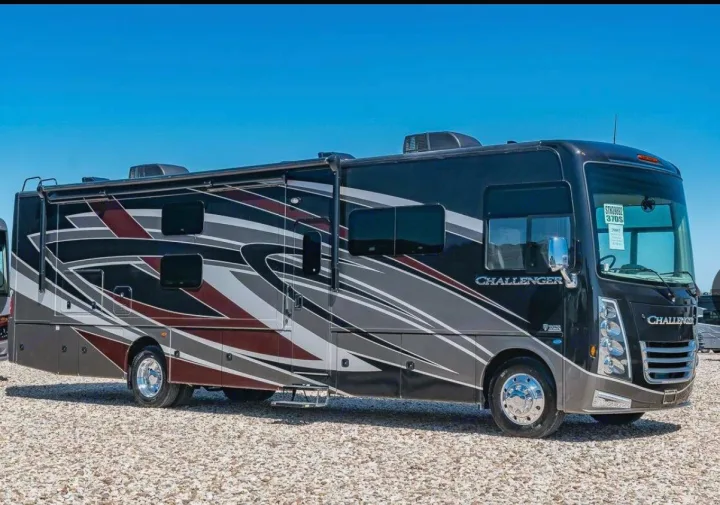 Stylish dark Class A Challenger rv rental motorhome with striking graphics parked on a gravel lot.. Thor Motor Coach Challenger 2019