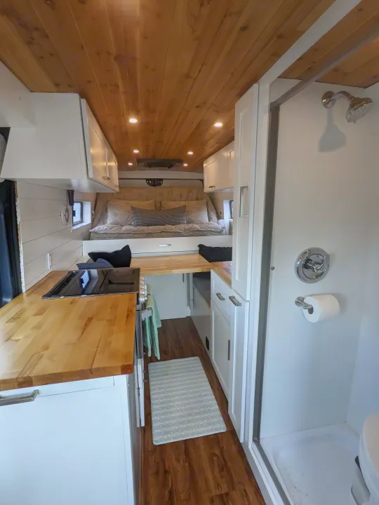 An inviting RV rental interior showcases a full kitchen, comfortable bed, and compact shower, ideal for adventurous travel.. RAM Promaster 2019