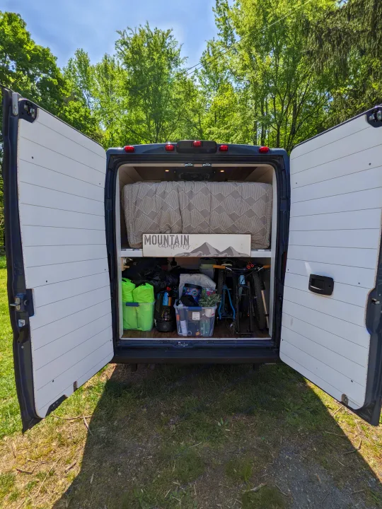 Inside an RV rental: organized camper van with bed, gear storage, and bikes for your next mountain camping trip.. RAM Promaster 2019