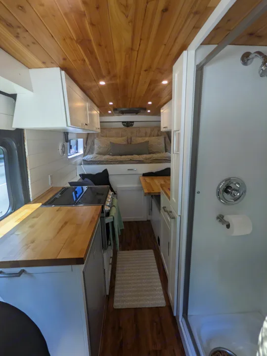 Step inside this RV rental: a modern space with wooden ceilings, white cabinets, a full kitchen, a comfy bed, and a shower.. RAM Promaster 2019