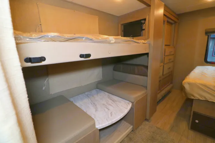 Spacious RV rental interior featuring bunk beds, a convertible dinette, TV, and a cozy bedroom area.. Thor Coleman 2021