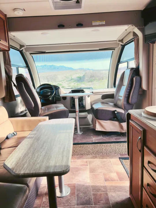 Spacious RV rental interior with cockpit, living area, and scenic desert mountain view from the front window.. Thor Vegas 2017