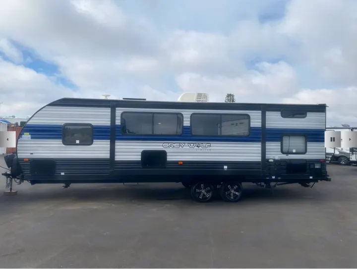 Side view of a Grey Wolf Cherokee travel trailer, ideal for rv rental, showcasing its blue and gray exterior design.. Forest River Cherokee Grey Wolf 2021