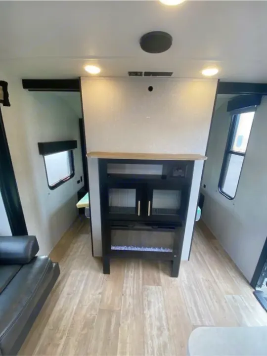 Spacious RV rental living area featuring a modern entertainment unit with fireplace, bright lighting, and wood-look flooring.. Forest River Cherokee Grey Wolf 2021