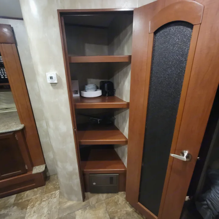 RV rental: Organized storage featuring wooden cabinet, multiple open shelves with items, and a control panel.. Winnebago Ultralite 2014