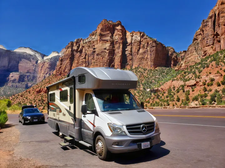 Winnebago RV rental parked in Zion National Park, with majestic red rock formations and a clear blue sky.. Winnebago View 2017