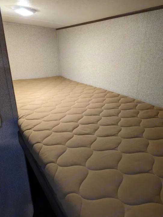 Compact RV rental bunk bed with quilted mattress, offering a comfortable sleeping area for your travels.. Coachmen Apex Nano 2019