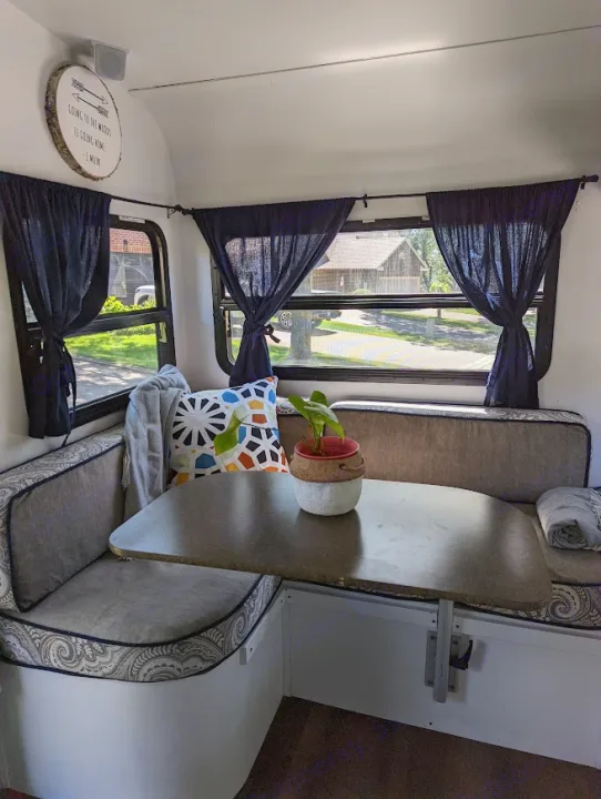Inside a cozy RV rental: a bright dinette area with patterned cushions, practical table, and blue curtains.. Gulf Stream Vista Cruiser M-19RSD 2013
