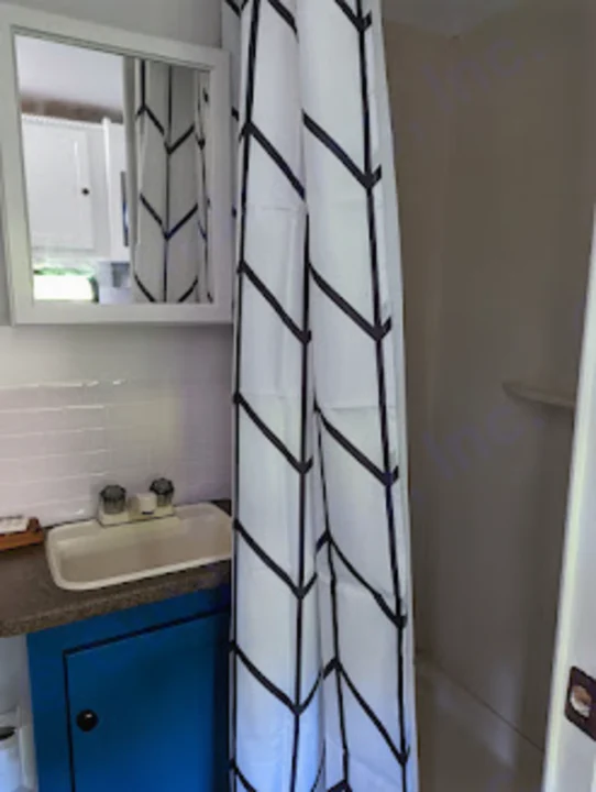 RV rental compact bathroom: white sink on blue cabinet, mirrored medicine cabinet, and black/white chevron shower curtain.. Gulf Stream Vista Cruiser M-19RSD 2013