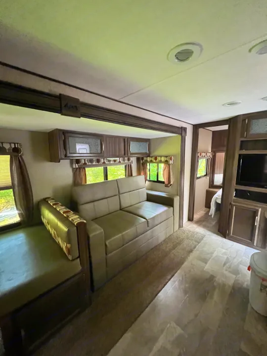 Comfortable RV rental interior with living area, sofa, and dinette. Includes multiple windows and a TV.. Coachmen Apex 2018
