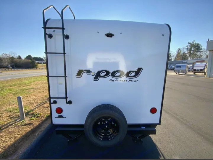 Rear view of a white r-pod travel trailer, featuring a ladder and spare tire. Ideal for your next RV rental adventure.. Forest River R POD 193  H.R. EDITION 2022