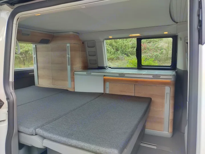 RV rental interior: cozy fold-out bed, integrated kitchenette & storage. Perfect for travel adventures.. Volkswagen California Coast T6.1 DSG7 2023