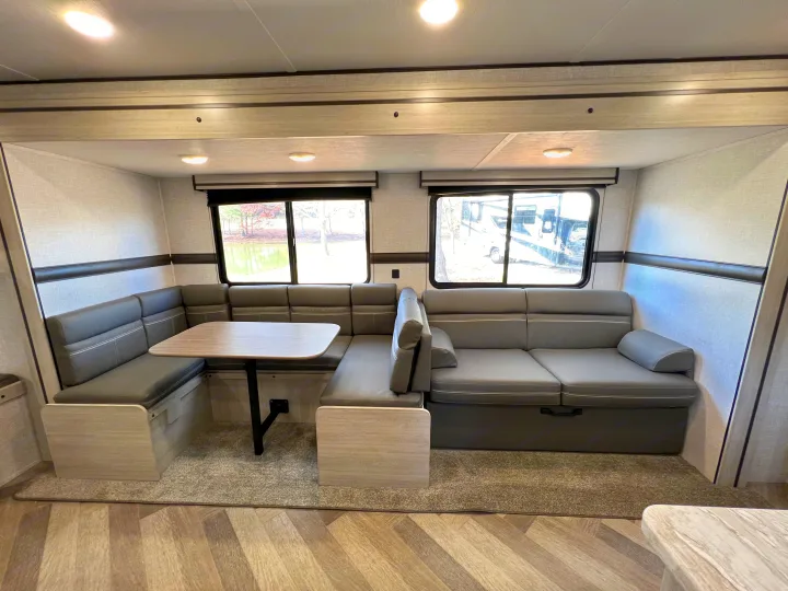 Spacious RV rental interior featuring a large, cozy U-shaped dinette/sofa and bright windows.. Crossroads Zinger 2023