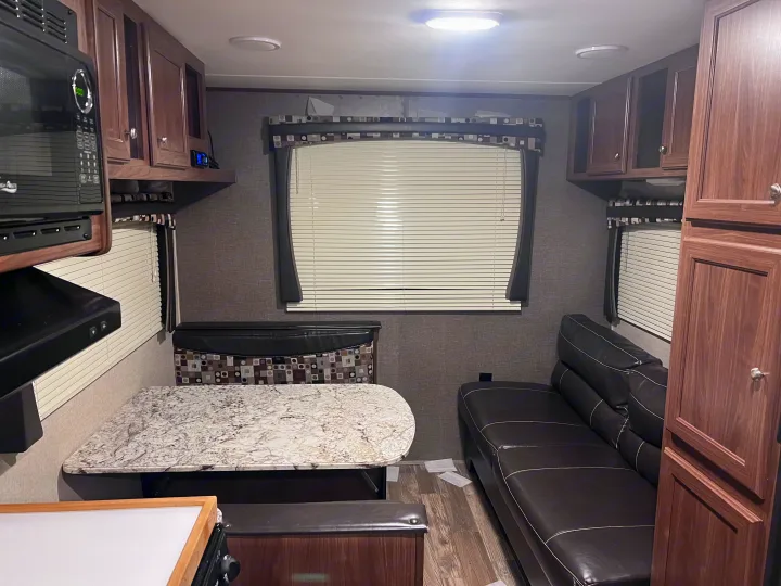 Explore this functional RV rental interior: microwave, dinette, and cozy sofa. Perfect for your next road trip adventure.. Heartland RVs Pioneer 2016