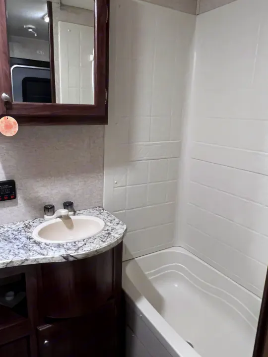 Compact RV rental bathroom with a sink, mirror reflecting the RV interior, and a tub/shower combo.. Heartland RVs Pioneer 2016