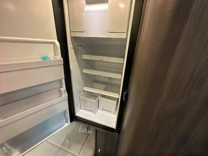 This empty rv rental refrigerator awaits your groceries. Featuring interior shelves, door storage, and crisper bins.. Airstream Interstate 2021