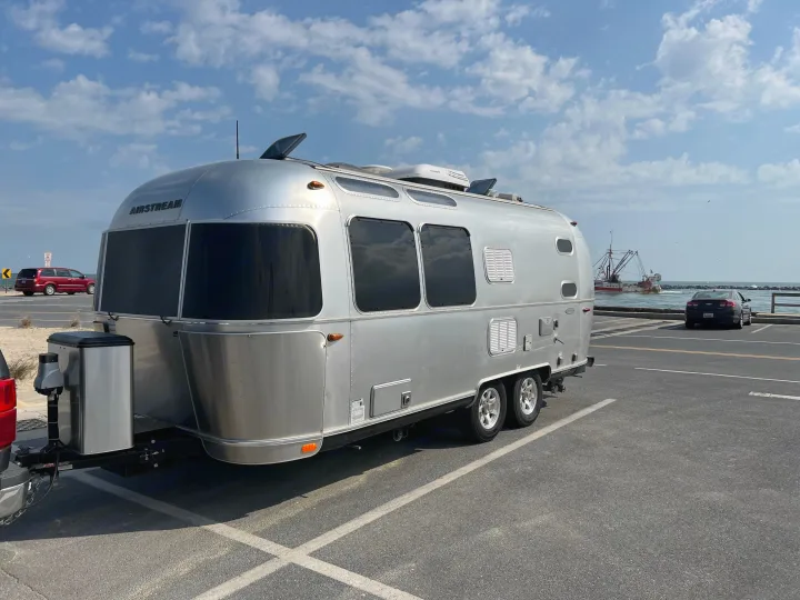 A shiny Airstream rv rental travel trailer parked by the water, ideal for exploring coastlines and adventures.. Airstream Flying Cloud 2017