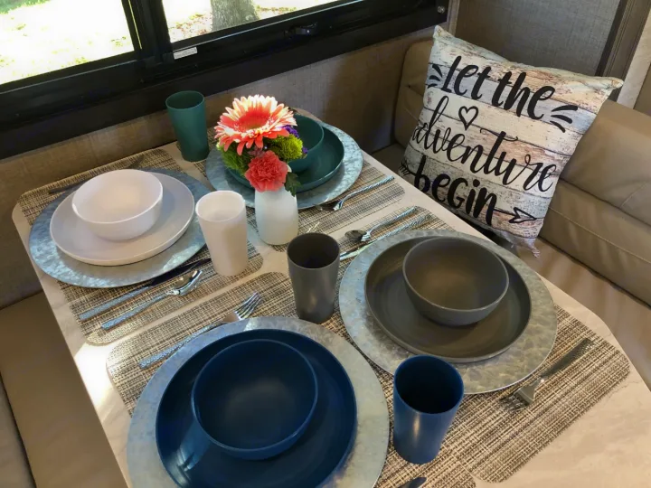 Cozy RV rental dining area, fully set with dinnerware and flowers, ready for your next adventure.. Jayco Redhawk 2023