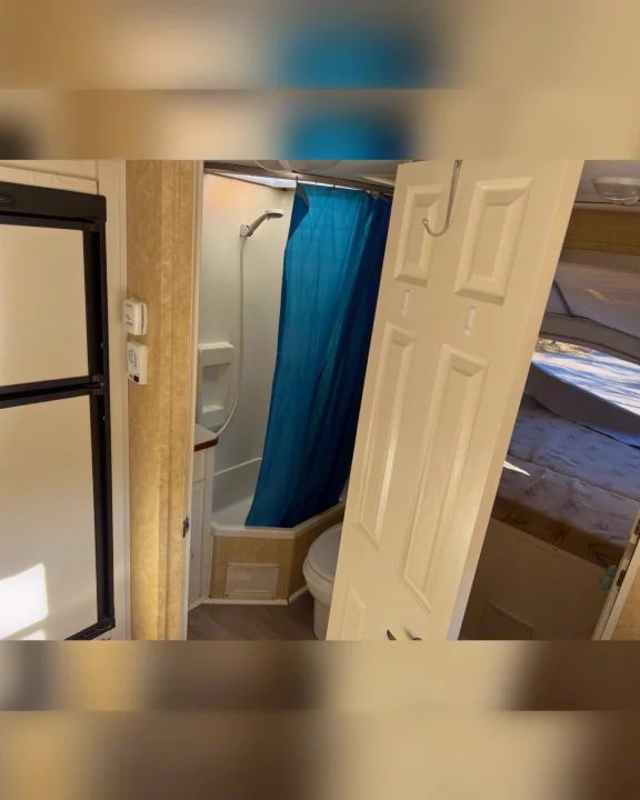 Explore this RV rental's interior: a compact bathroom with shower and toilet, a refrigerator, and a cozy bed area.. Starcraft Antigua 2007