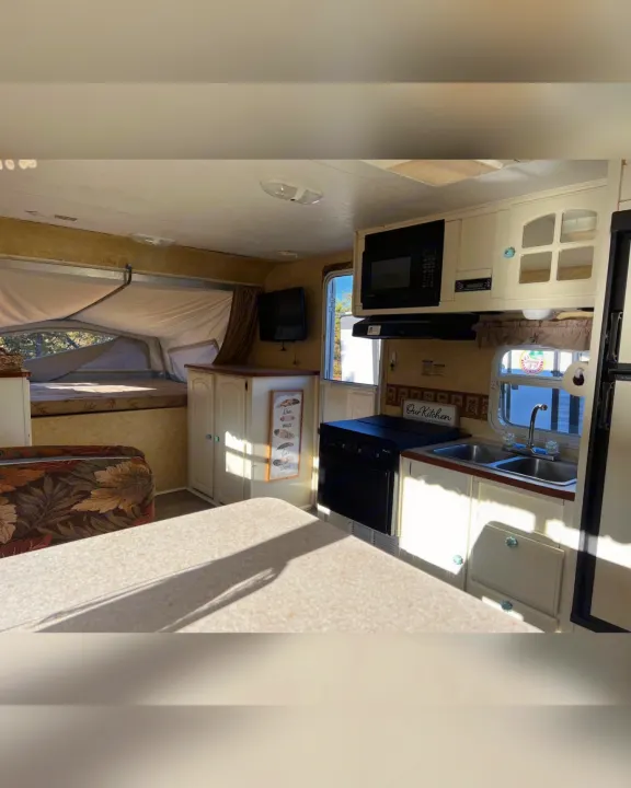 Bright RV rental interior showcasing a full kitchen, pop-out bed, and comfortable living space with natural light.. Starcraft Antigua 2007