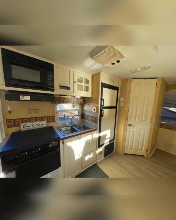 Explore this RV rental's equipped kitchen with microwave, stove, double sink, fridge, and cabinet storage.. Starcraft Antigua 2007