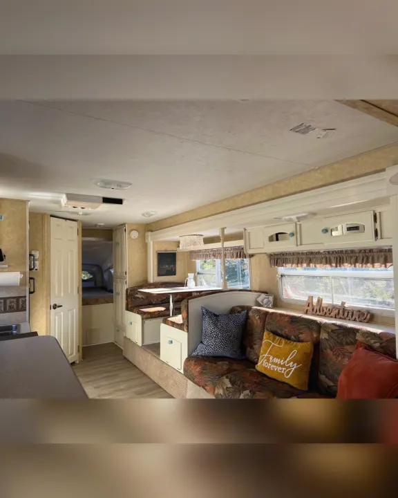Cozy RV rental interior with a dining booth, kitchen, and bedroom access, ideal for family travel adventures.. Starcraft Antigua 2007