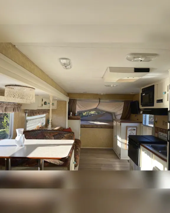 Spacious RV rental interior with bright dining booth, full kitchen, and a cozy pop-out bed. Ideal for your travel adventures.. Starcraft Antigua 2007