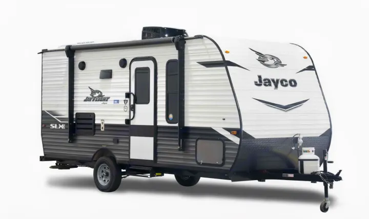 A white and gray Jayco Jay Flight SLX travel trailer, ideal for RV rental. Features awning, door, windows, and propane tank.. Jayco Jay Flight SLX 2022