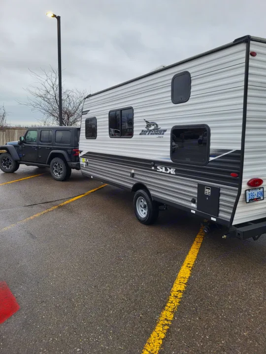 A black Jeep Wrangler tows a Jay Flight SLX travel trailer, resembling an RV rental. Ready for new adventures.. Jayco Jay Flight SLX 2022