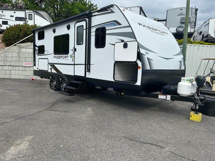 A white Passport travel trailer RV, ready for your next RV rental or camping trip. Front storage open.. Keystone Passport 2022