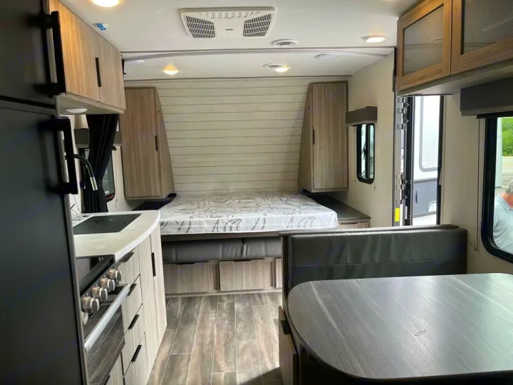 Spacious RV rental interior with a bed, kitchen, and dining booth. Perfect for road trips and camping.. Keystone Passport 2022