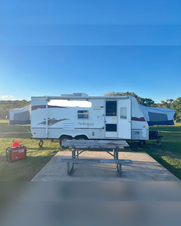 Antiqua hybrid RV rental set up at a sunny campsite, with a generator and picnic table.. Starcraft Antigua 2007