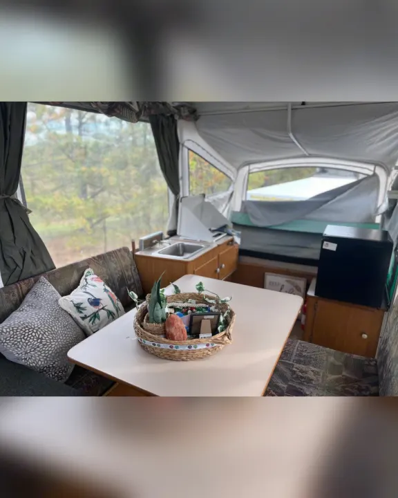Experience comfortable camping in this RV rental! Pop-up camper interior features dining, kitchen, and scenic views.. Fleetwood Other 2005