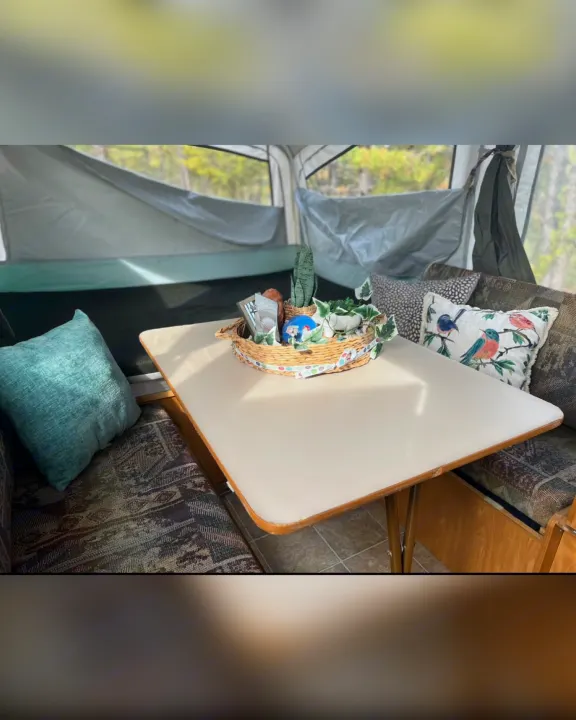 Cozy RV rental interior with dining area, comfy cushions, and nature views from a pop-up camper setup.. Fleetwood Other 2005