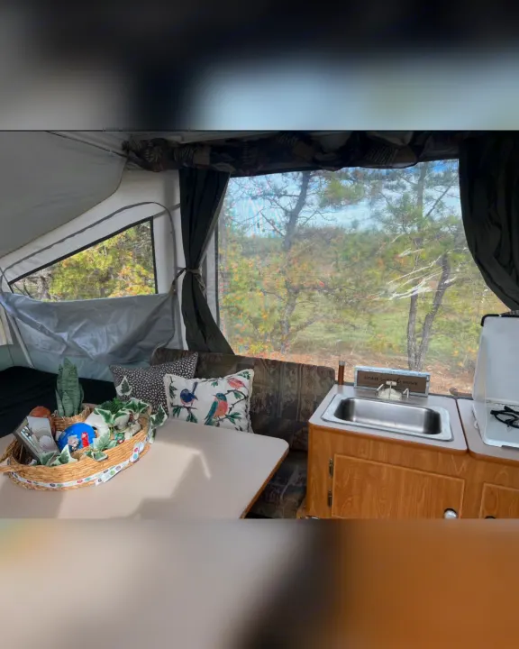 Cozy RV rental interior with dining, kitchen, and nature views through large windows, ideal for travel.. Fleetwood Other 2005