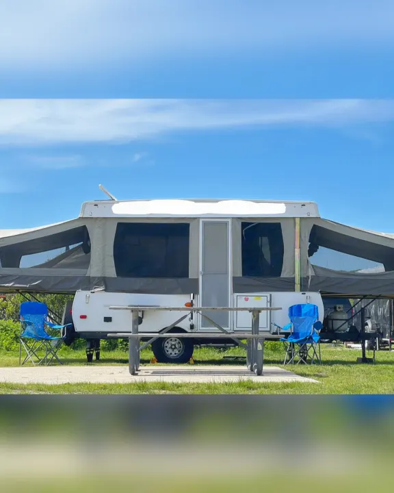 Pop-up camper RV rental set up at a sunny campsite with a picnic table and chairs under a clear blue sky.. Flagstaff/ForestRiver M.A.C.SeriesM-228 2016