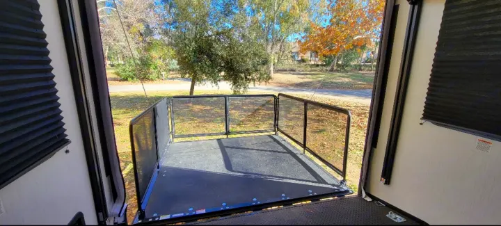 RV rental with an expansive rear patio deck, offering outdoor views of trees and a road.. Heartland Torque 2022