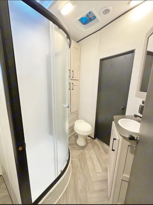 Modern RV rental bathroom with a frosted glass shower, toilet, and sink vanity, designed for travel comfort.. Heartland Torque 2022