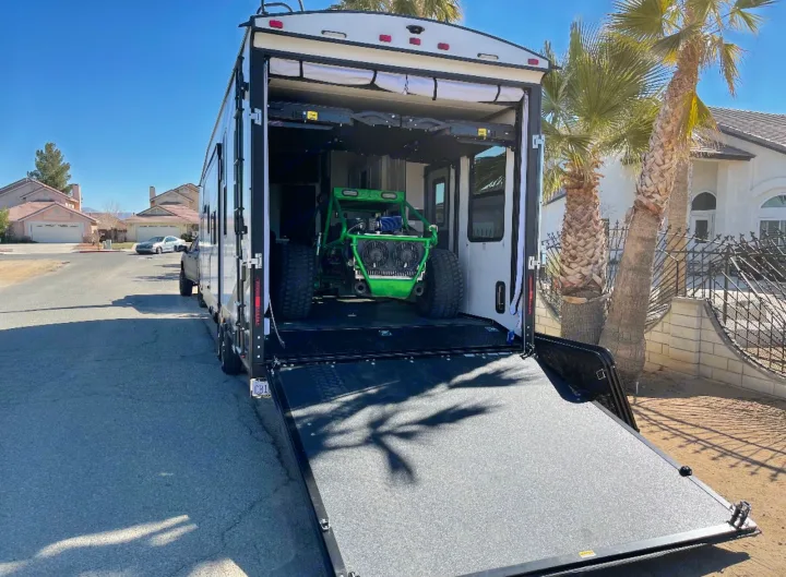 Spacious RV rental toy hauler with rear ramp down, showcasing a vibrant green off-road buggy inside. Ready for action!. Heartland Torque 2022