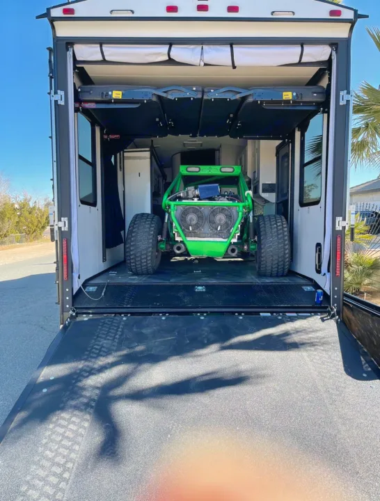 RV rental toy hauler open, revealing a green off-road buggy parked inside. The back ramp is down, ready for adventure.. Heartland Torque 2022