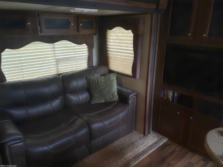 Cozy RV rental interior with a brown leather sofa, entertainment center, and overhead storage cabinets.. Keystone Cougar Xlite 2020