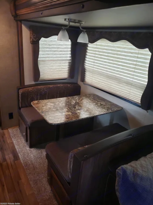 Cozy RV rental dinette with dark wood benches, a granite-look table, and large windows with blinds.. Keystone Cougar Xlite 2020