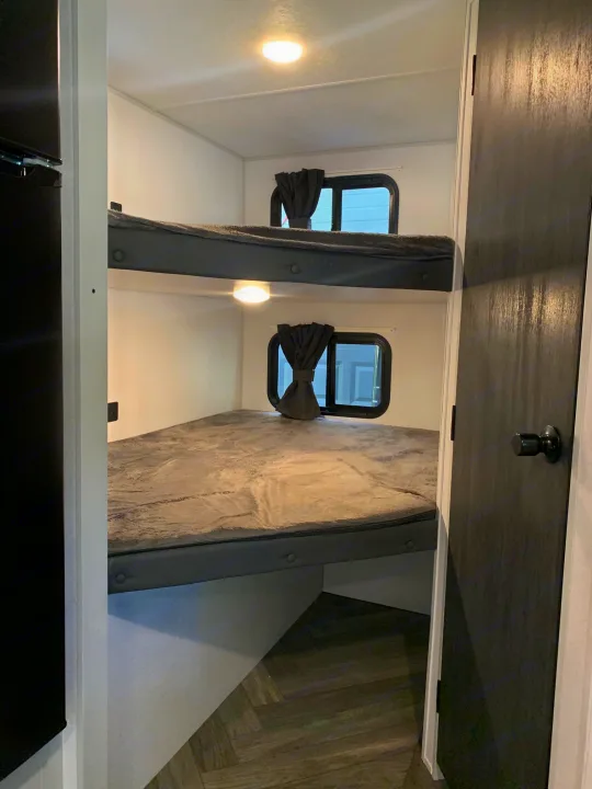 Cozy RV rental bunk beds: two modern bunks with windows, lights & grey accents. Perfect for family adventures.. Forest River Salem FSX 2021