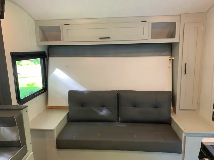 RV rental: Bright interior with a black convertible sofa/Murphy bed, light gray overhead cabinets, and a side window.. Forest River Salem FSX 2021