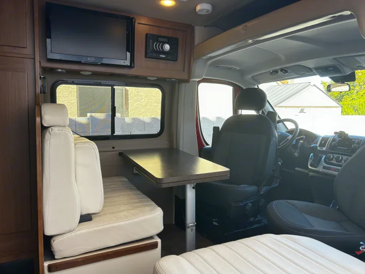 Explore this RV rental's inviting interior: dinette, entertainment, and cockpit for comfortable travel.. Winnebago Travato 2015