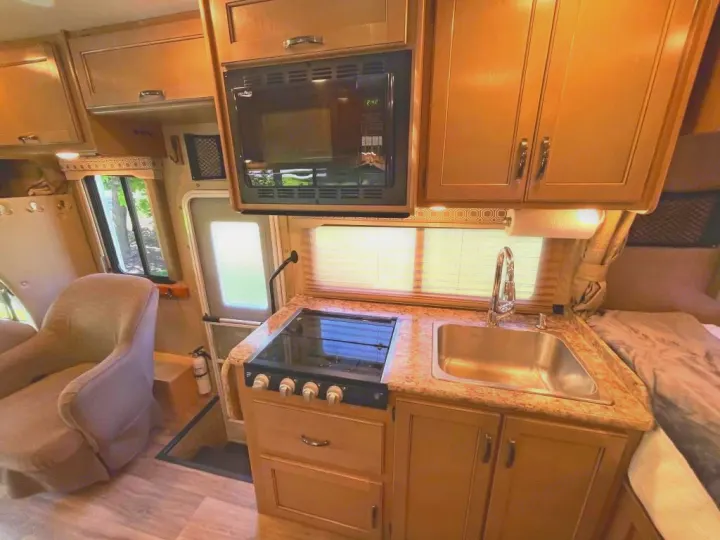Experience this rv rental's functional interior: a full kitchen with sink, stove, microwave, and cozy living space.. Thor Motor Coach Four Winds 2019