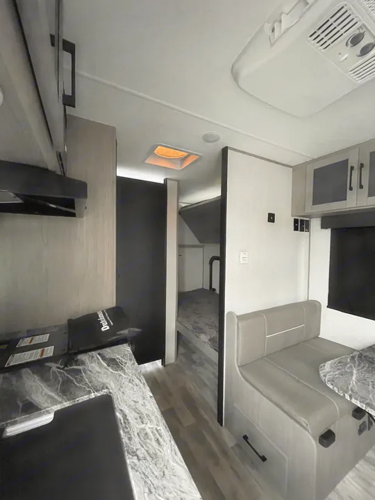 Modern RV rental interior showcasing a well-equipped kitchen, dining area, and cozy bunk beds.. Dutchmen Kodiak Cub 175BH 2022