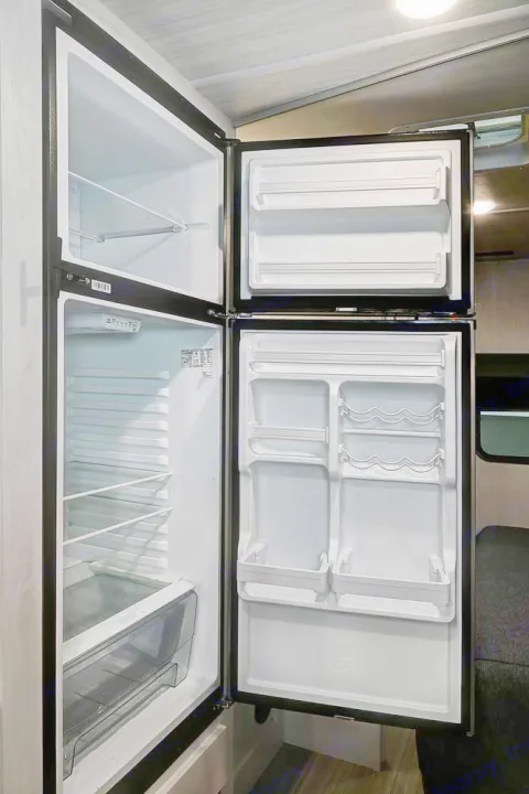 Clean, open refrigerator and freezer in this RV rental, showcasing interior shelves and door storage options.. Forest River Entrada 2022
